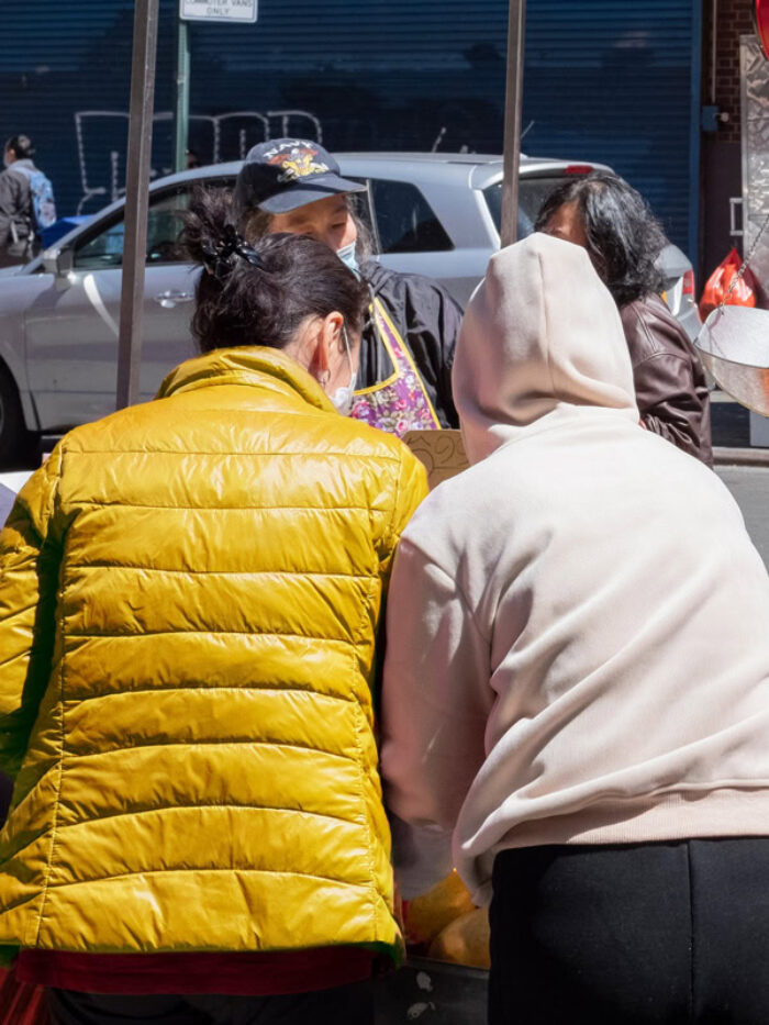Two people facing away are looking at produce at an outdoor stand