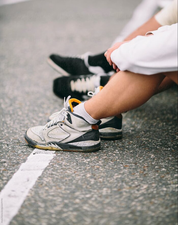 Legs of people sitting on the side of the street