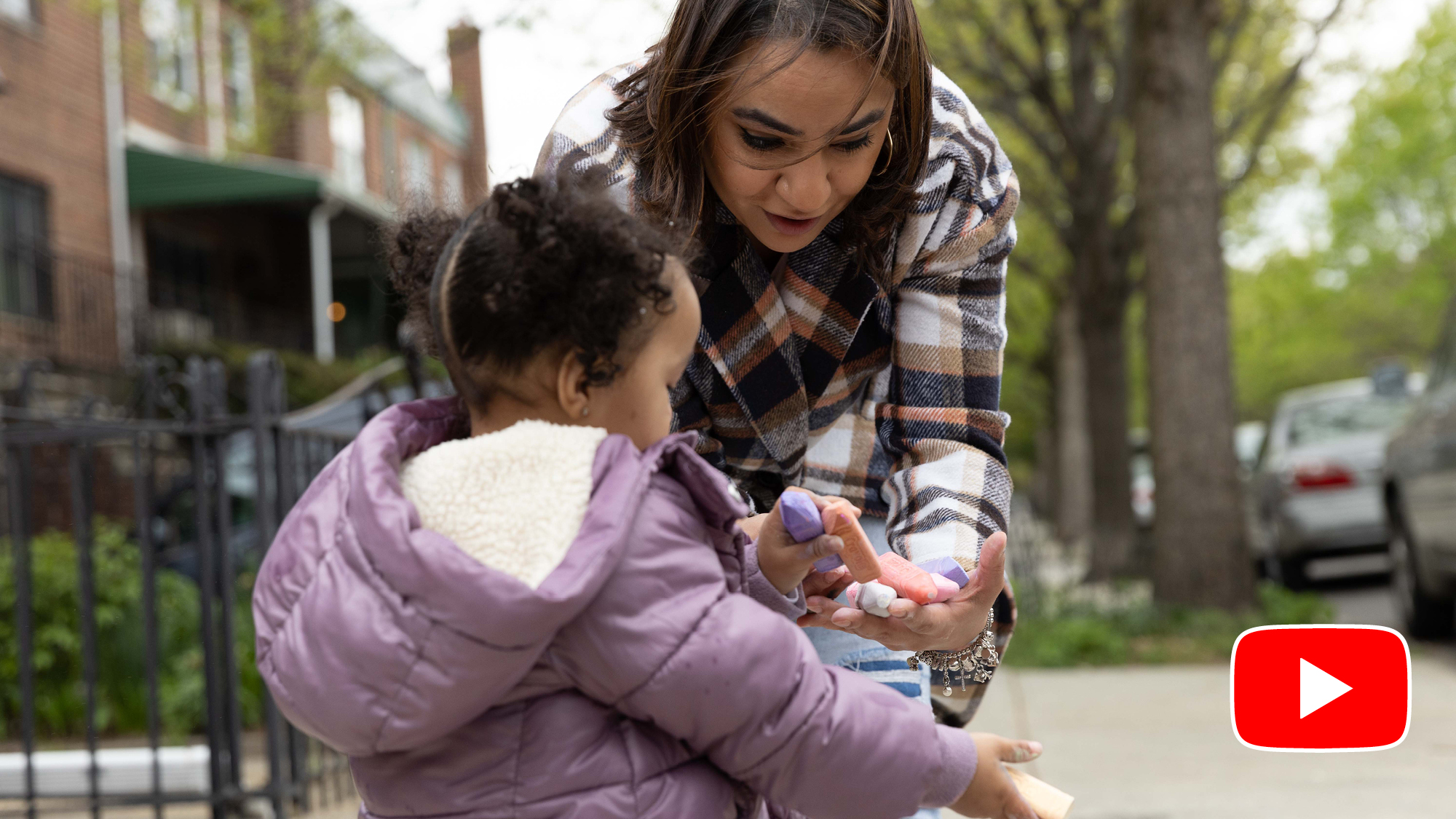 Still from a video on youtube with a mother and child looking at sidewalk chalk