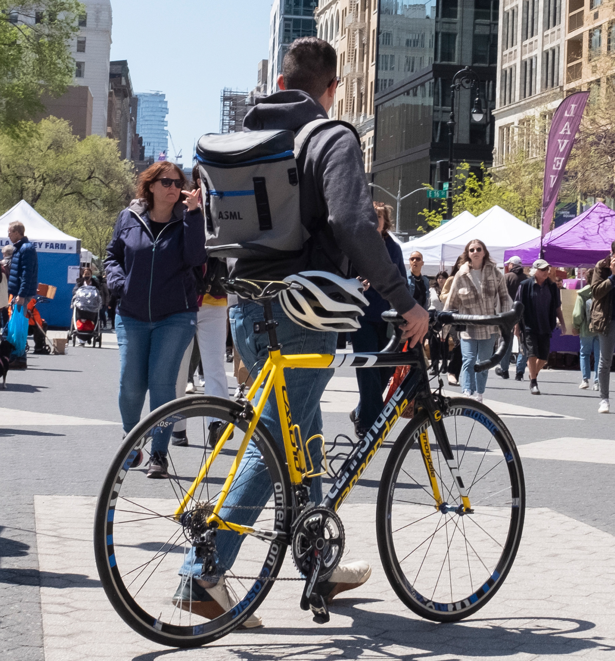 A man walking his bike at a farmers market.